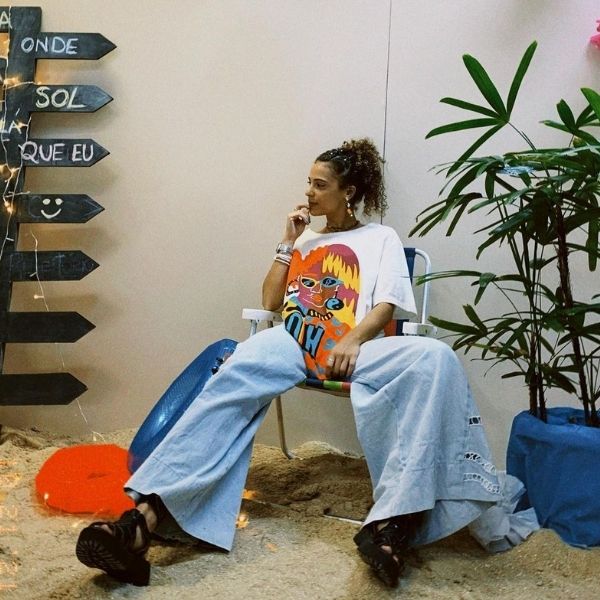 Mulher utilizando o estilo Aesthetic sentada em uma cadeira de praia. 